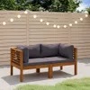 A wooden outdoor sofa with gray cushions is placed on a patio in front of a wooden fence decorated with string lights. Náhled obrázku produktu