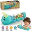 Teal Gear Caterpillar-Spielzeug mit durchsichtigen Segmenten, die bunte Zahnräder und Buchstaben zeigen, von einem Kind gehalten, mit seiner braunen Verpackungsbox im Hintergrund Anteprima dell’immagine prodotto