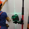 A person is using a laser level and a telescopic pole to mark lines on a wall. Náhled obrázku produktu