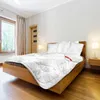 A bedroom scene with a neatly made bed featuring a white comforter with a subtle pattern. Podgląd zdjęcia produktu