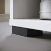A close-up view of the bottom of a white shelf unit, showing a black support block underneath. Anteprima dell’immagine prodotto
