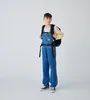 A young boy stands in front of a white background wearing denim overalls and a tie-dye shirt, with a black backpack on. Podgląd zdjęcia produktu