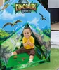 A young child is playing inside a dinosaur-themed play tent in a grassy outdoor area. Podgląd zdjęcia produktu