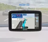 A TomTom navigation device is shown mounted on a car dashboard, displaying a route on a highway. Podgląd zdjęcia produktu
