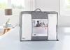 A white duvet is packaged in a gray carrying bag with a product label, placed on a bed. Produktbild-Vorschau