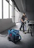 A man is using a circular saw connected to a vacuum cleaner in a construction environment. Anteprima dell’immagine prodotto