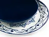 A close-up view of two plates, one stacked on top of the other, with a dark blue plate on top of a white plate with blue decorative patterns. Anteprima dell’immagine prodotto