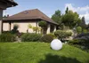 A garden scene with a house, landscaping, and a large white sphere on the lawn. Anteprima dell’immagine prodotto