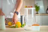 A person is preparing fruit in a kitchen, with a water filter pitcher and its filter cartridge on the counter. Náhľad obrázku produktu