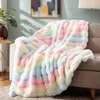 A fluffy, multicolored blanket draped over a sofa in a living room setting. Produktbild-Vorschau