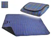 A folded and unfolded picnic blanket with a plaid pattern. Produktbild-Vorschau