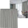 A close-up of a light gray curtain with pleats, with a room scene in the background. Produktbild-Vorschau