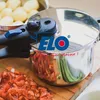 A close-up shot of a pressure cooker with chopped vegetables in the foreground. Produktbild-Vorschau