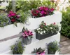 A white wooden planter filled with various flowering plants. Voir les images du produit