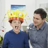 A father and son playing a game where the son wears a crown with forks and food items attached. Anteprima dell’immagine prodotto