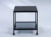 A black metal side table with a glass shelf and wheels, photographed against a light gray and white background. Produktbild-Vorschau