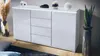A modern white sideboard with LED lighting is displayed in a living room setting, with decorative items and plants. Produktbild-Vorschau