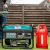 A person is using a generator in a backyard setting next to a propane tank. Podgląd zdjęcia produktu
