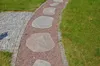 A garden path made of stepping stones and red gravel, bordered by cobblestones and grass. Produktbild-Vorschau