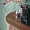 A close-up view of a wooden surface with decorative items on it, against a green grid-patterned background. Produktbild-Vorschau