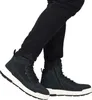 A person wearing black jeans and dark gray boots. Produktbild-Vorschau
