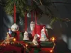 Christmas ornaments and gifts displayed under a pine branch. Produktbild-Vorschau