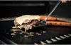 A close-up of a hamburger with cheese being cooked on a grill, with hot dogs in the background. Produktbild-Vorschau