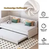 A white sofa bed with a pull-out trundle bed is shown in a room with a patterned rug. Decorative pillows and a stuffed panda are on the sofa. Inset images and icons highlight product features. Produktbild-Vorschau