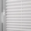 A close-up view of white pleated blinds with a white handle on the left side. Produktbild-Vorschau