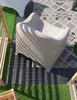 An outdoor seating area with a modern chair on a patterned rug and artificial grass. Produktbild-Vorschau