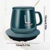 A teal mug with a lid and spoon sits on a black and teal warming coaster with a digital display. Produktbild-Vorschau
