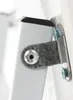 A close-up view of a metal hinge mechanism connecting two white components, secured by screws. Náhľad obrázku produktu