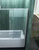 A close-up view of a shower screen installed on a bathtub, with green tiled walls in the background. Produktbild-Vorschau