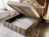 A bed with its storage compartment open, showing the interior space. The bed is upholstered in a textured fabric and has a modern design. The scene is set in a bedroom with soft lighting. Produktbild-Vorschau