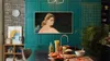 A modern kitchen with a TV displaying artwork above a sink and counter. Produktbild-Vorschau