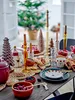 A festive table setting with Christmas decorations, including a tree in the background. Produktbild-Vorschau