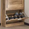 A close-up view of a wooden shoe cabinet with several pairs of shoes inside. Voir les images du produit