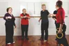 Four older women are playing a ring toss game indoors, possibly in a community center or gym. Produktbild-Vorschau