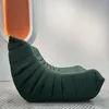 A green sofa is placed on a rug in front of a white wall with an orange illuminated oval shape. Voir les images du produit