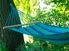 A hammock strung between trees in a natural outdoor setting. Produktbild-Vorschau