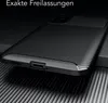 A black carbon-look phone case is shown from a diagonal angle on a ribbed dark surface. Produktbild-Vorschau