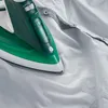 A close-up shot of a green and white steam iron resting on a white shirt. Produktbild-Vorschau
