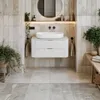 A modern bathroom vanity with a sink, drawers, and surrounding tiled walls and floor, featuring plants and towels. Náhled obrázku produktu