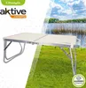 A portable table set up on grass with a lake and trees in the background. Produktbild-Vorschau