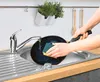 A person is washing a black pan in a kitchen sink under running water. Anteprima dell’immagine prodotto