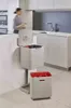 A modern kitchen scene with a woman interacting with a multi-compartment trash and recycling unit. Podgląd zdjęcia produktu