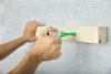 A person is using a spray marker to mark a wooden plank attached to a wall. Náhľad obrázku produktu