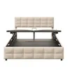 A beige upholstered bed frame with its storage mechanism partially open, shown against a white background. Produktbild-Vorschau