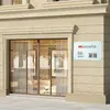 A sign with company information and QR codes mounted on the exterior wall of a building next to a storefront. Náhľad obrázku produktu