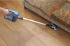 A hand holds a cordless vacuum cleaner and vacuums under a couch. Produktbild-Vorschau
